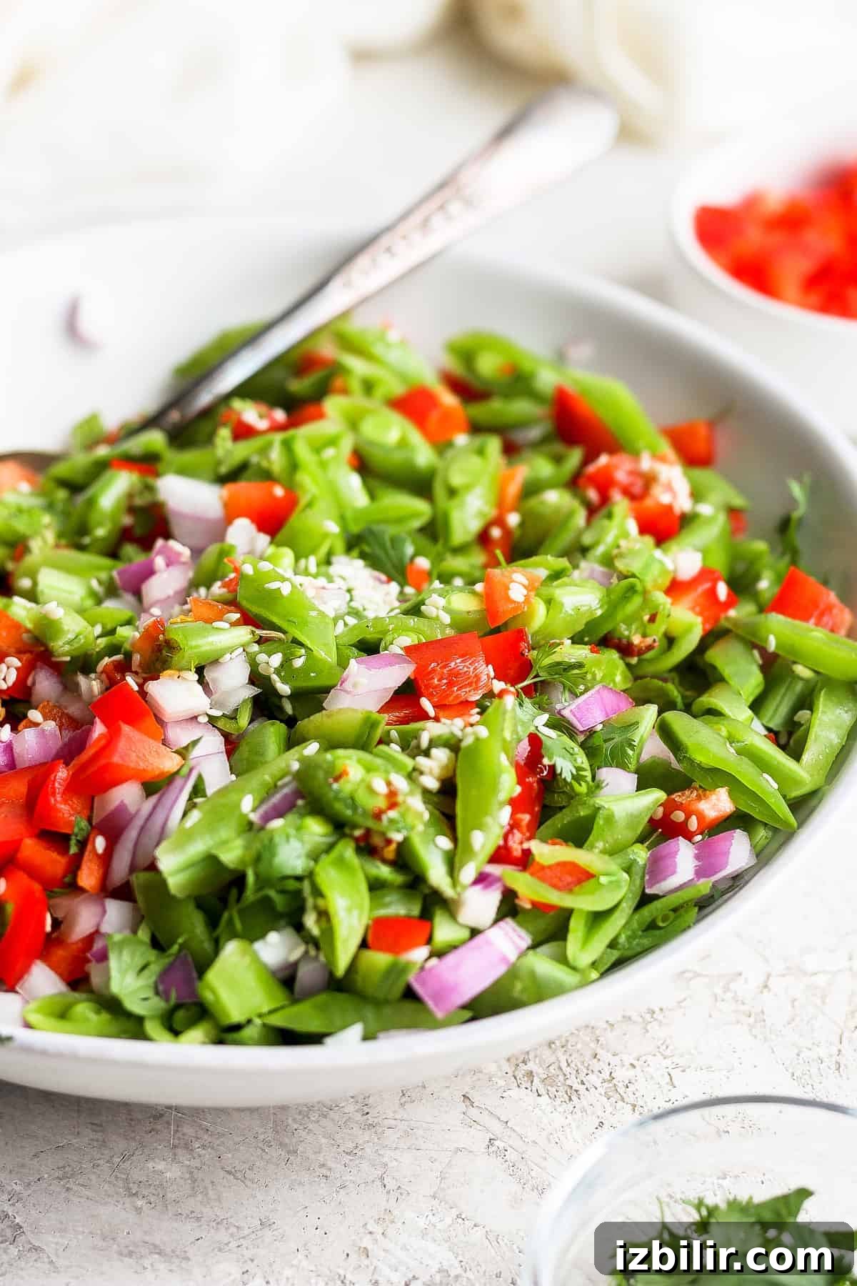 Ginger pea salad in a bowl topped with sesame seeds.