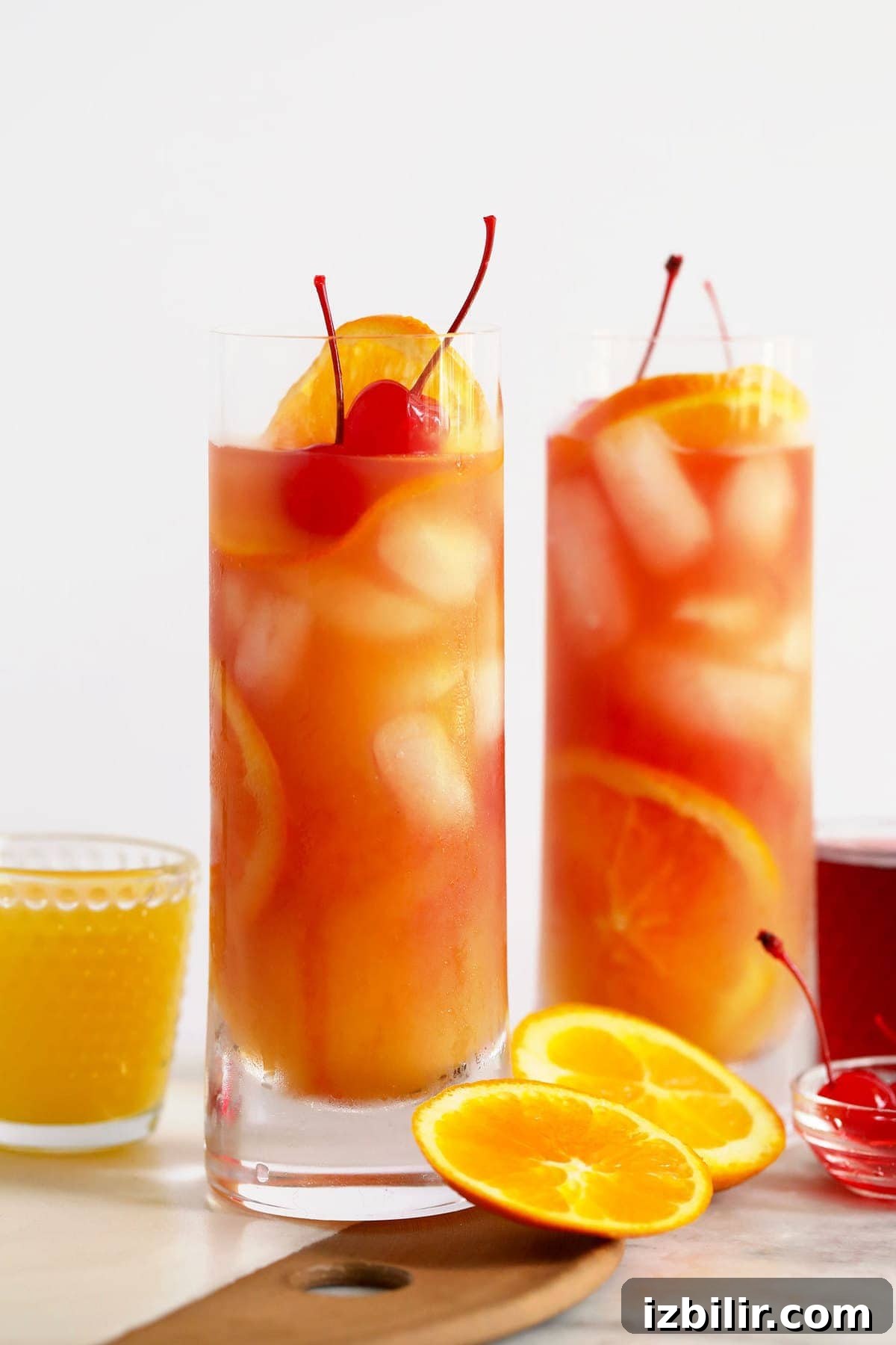 Two sex on the beach cocktails with oranges and cherries.