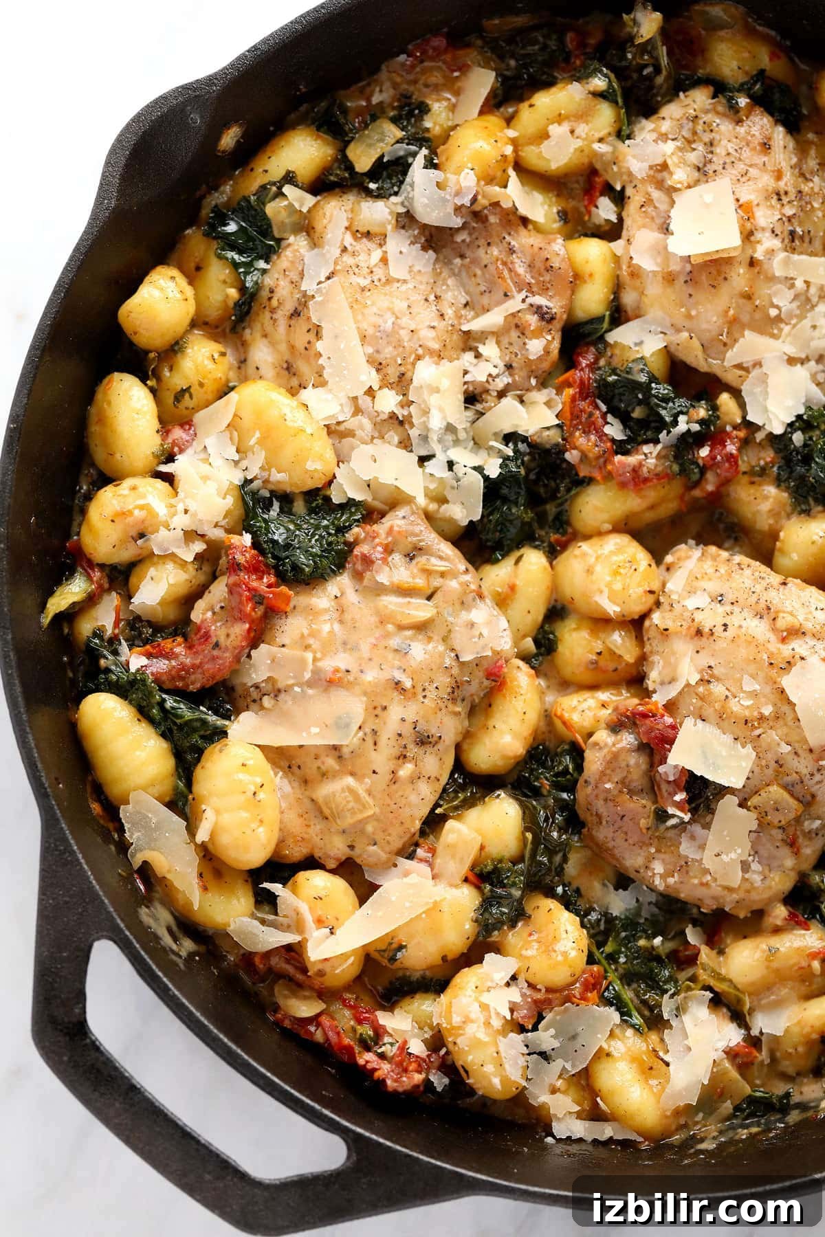 creamy tuscan chicken and gnocchi in a cast iron skillet ready to be served
