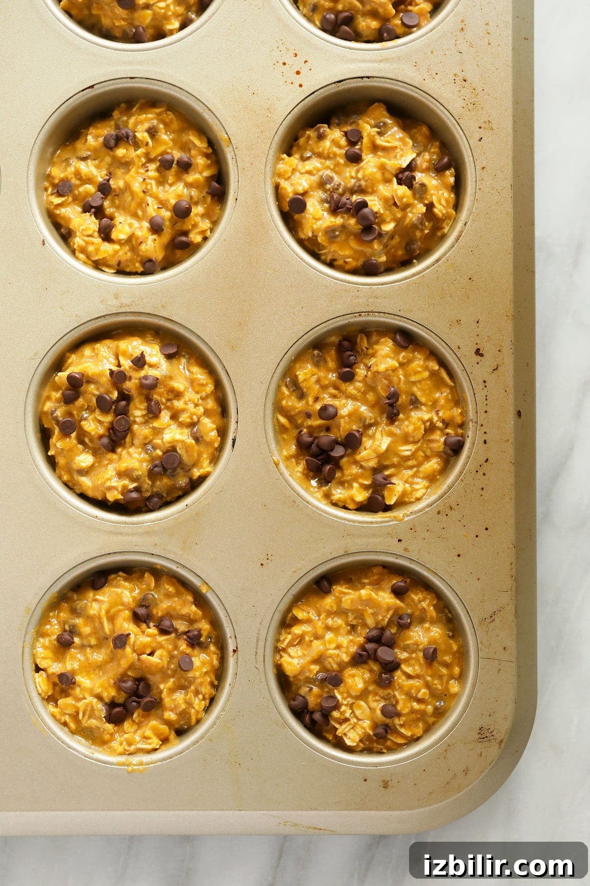 Make Ahead Pumpkin Oatmeal Cups Recipe 3 Pumpkin oatmeal cups in a muffin tin ready to go in the oven.