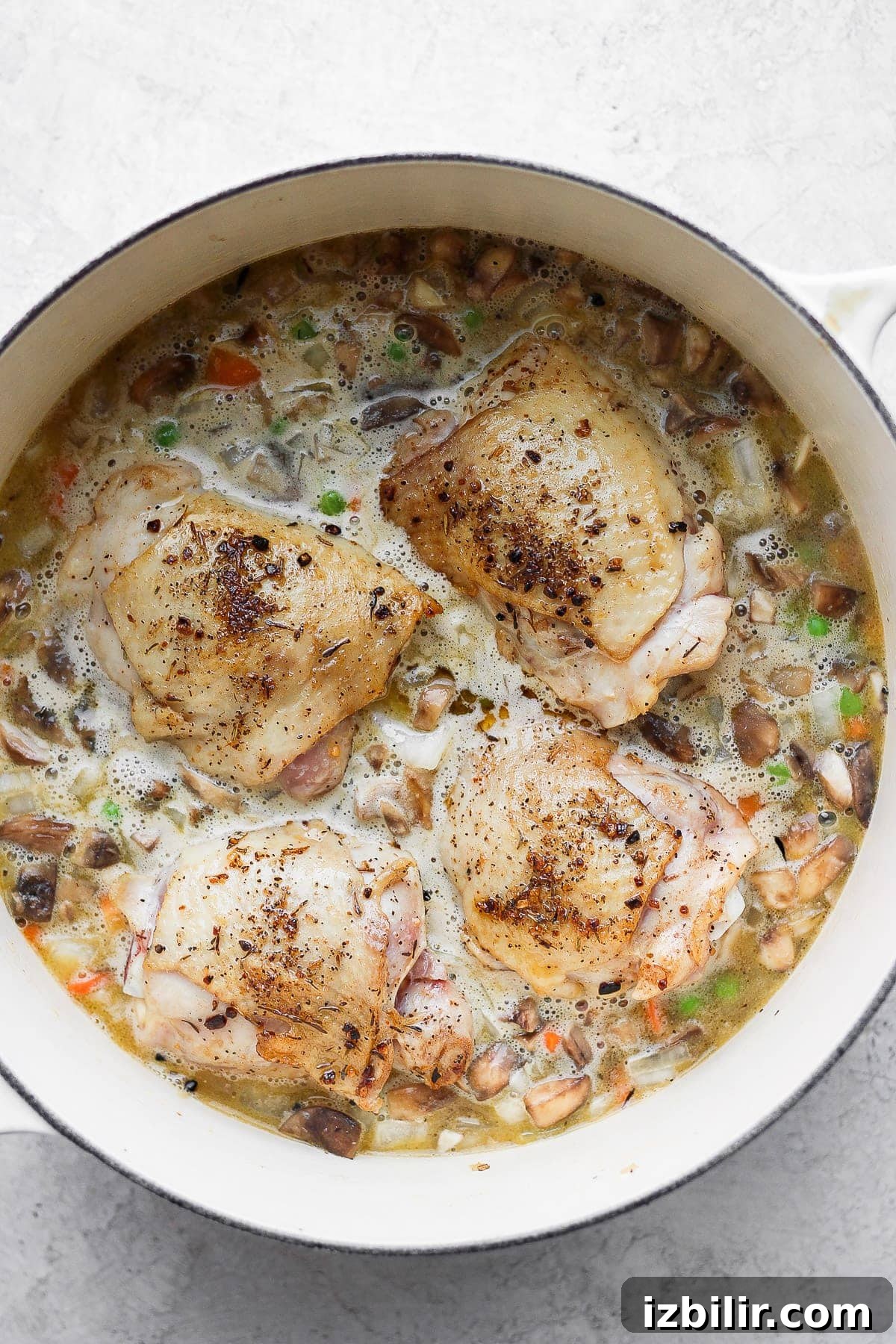 A flavorful chicken and rice recipe made with juicy chicken thighs and the most flavorful rice medley you've ever had! And, yes, it includes tons of veggies! uncooked rice with seared chicken thighs on top.