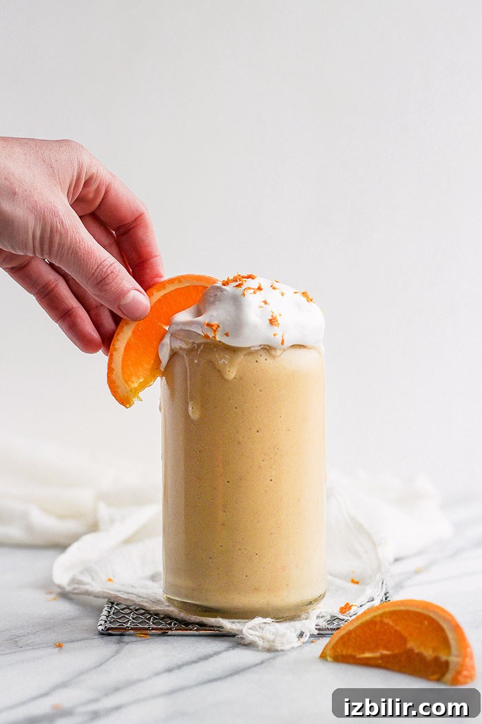 Looking for the orange smoothie of your dreams? Try our magical vitamin C-packed Orange Creamsicle Smoothie. You only need 3 ingredients + a few nummy add-ins! orange creamsicle smoothie with hand on orange slice