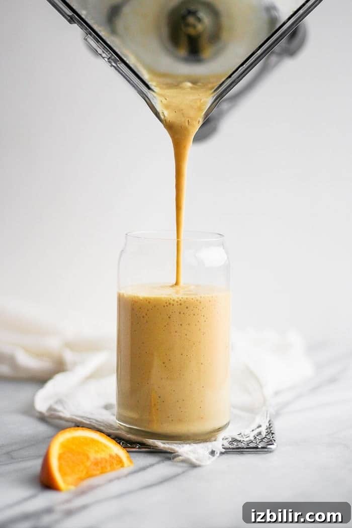 Looking for the orange smoothie of your dreams? Try our magical vitamin C-packed Orange Creamsicle Smoothie. You only need 3 ingredients + a few nummy add-ins! pouring orange smoothie into glass