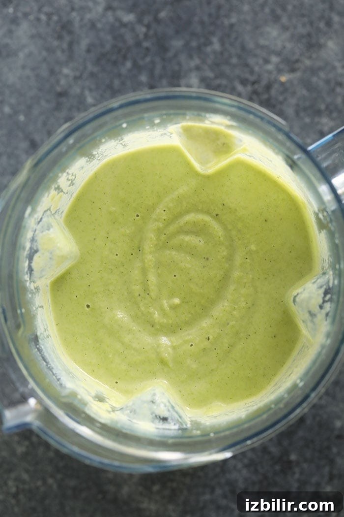 Creamy Broccoli and Cauliflower Cheese Soup Recipe 3 A green liquid in a blender that has been lightened up.