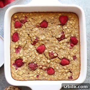 A white baking dish with raspberries, oats, and banana oatmeal toppings.