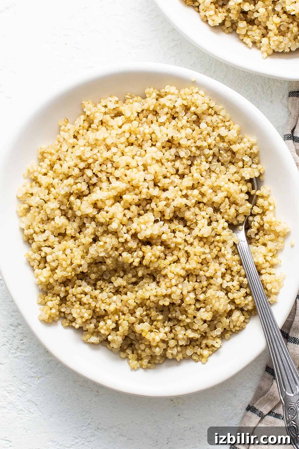 Cook quinoa in the microwave using a white bowl and a fork.