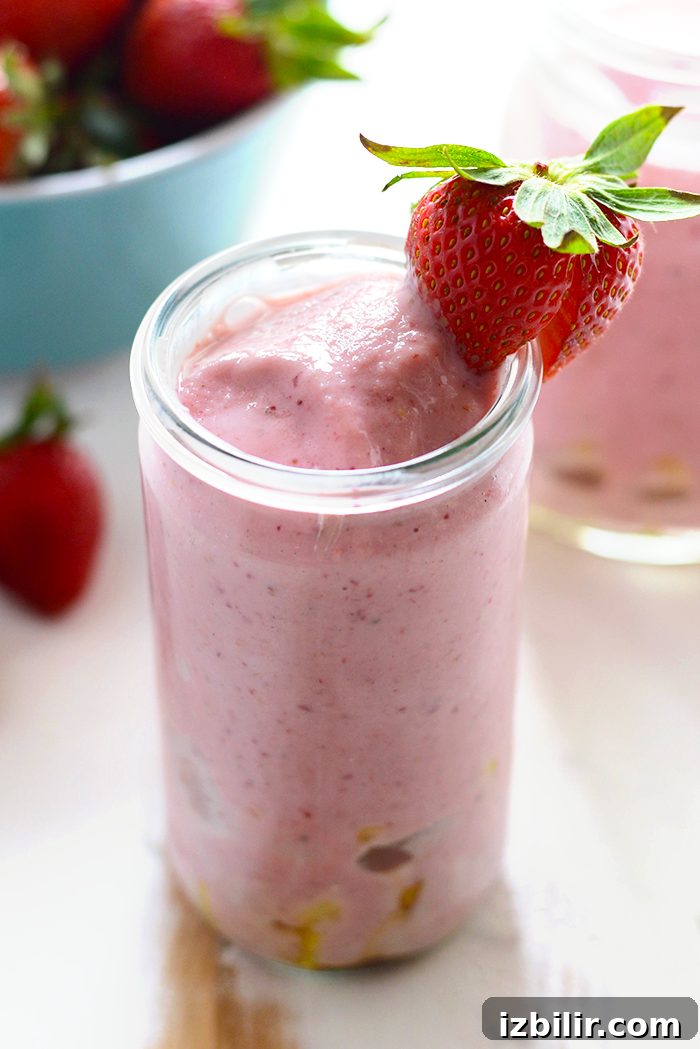 strawberry pineapple smoothie with strawberry on rim