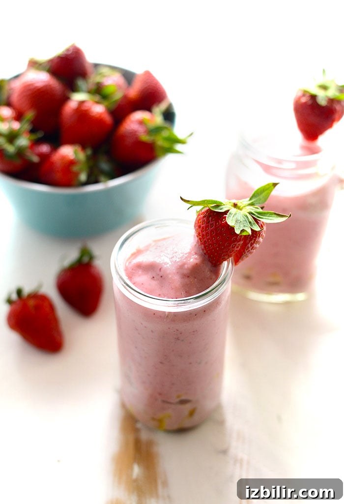 strawberry smoothie with pineapple chunks and whole strawberries in bowl