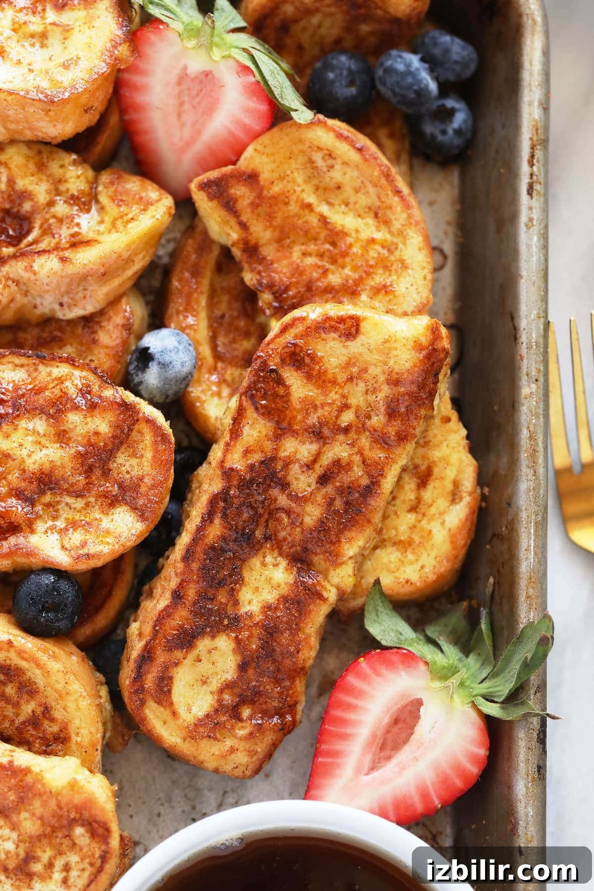 French toast sticks on a baking sheet with strawberries