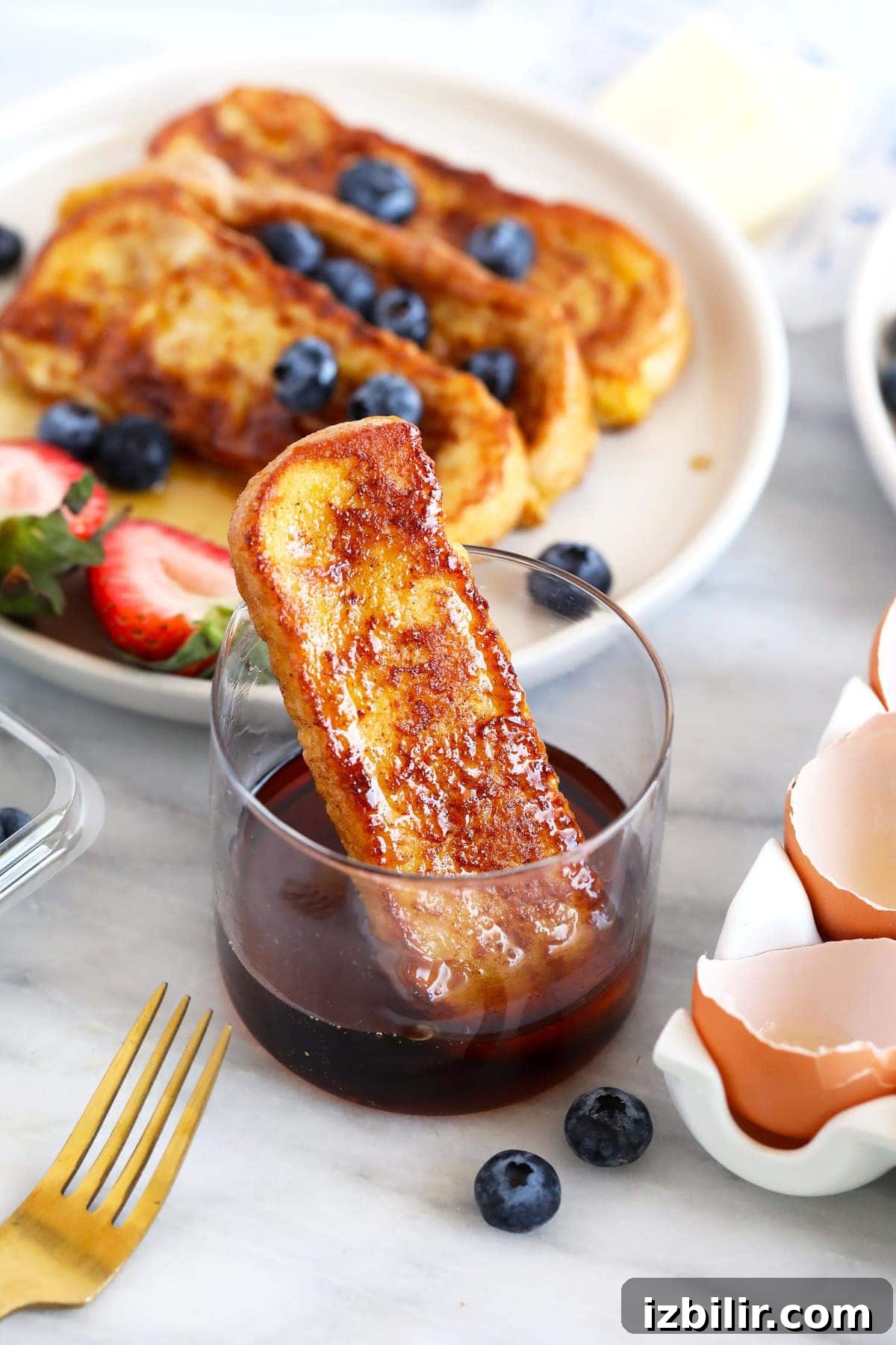 French toast stick in a cup of maple syrup
