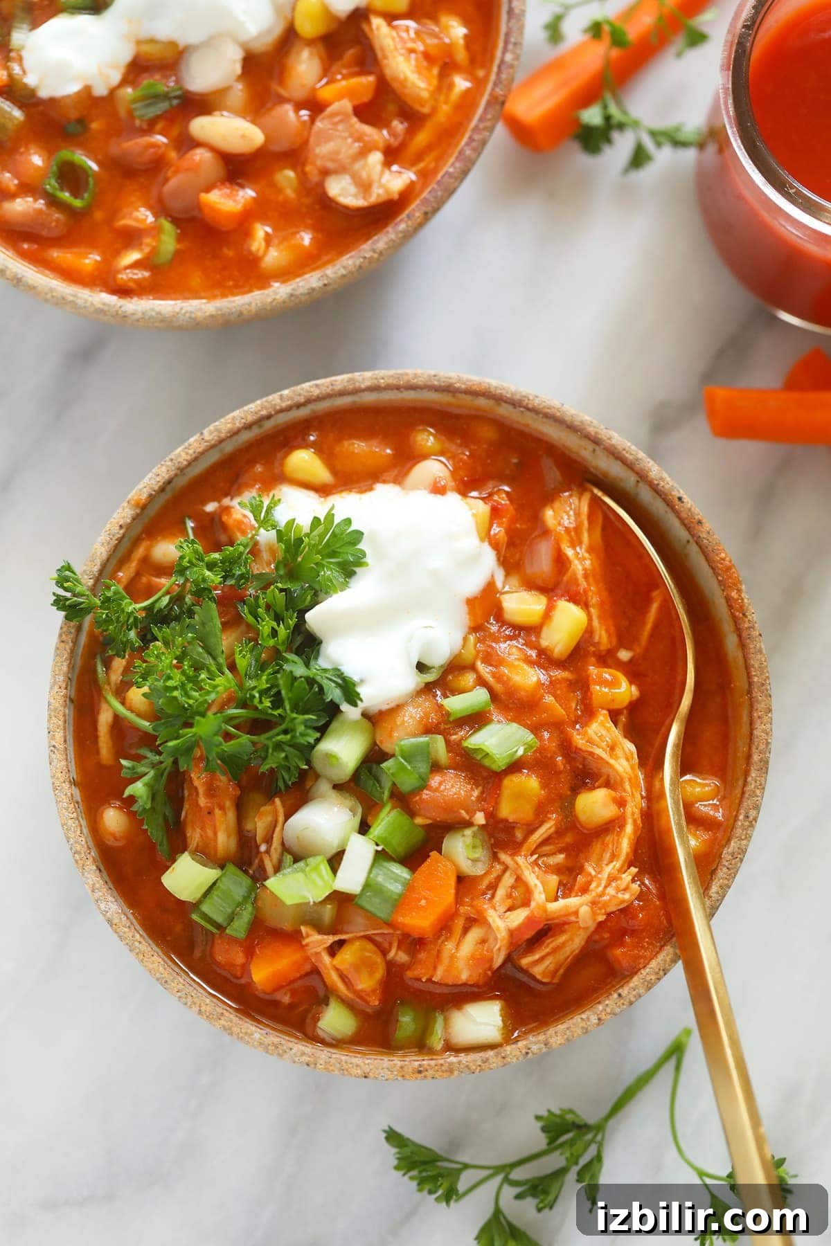 Your new favorite chili recipe is here! Try our incredible Instant Pot Buffalo Chicken Chili topped with a delicious Greek Yogurt blue cheese dressing. buffalo chicken in bowl with spoon