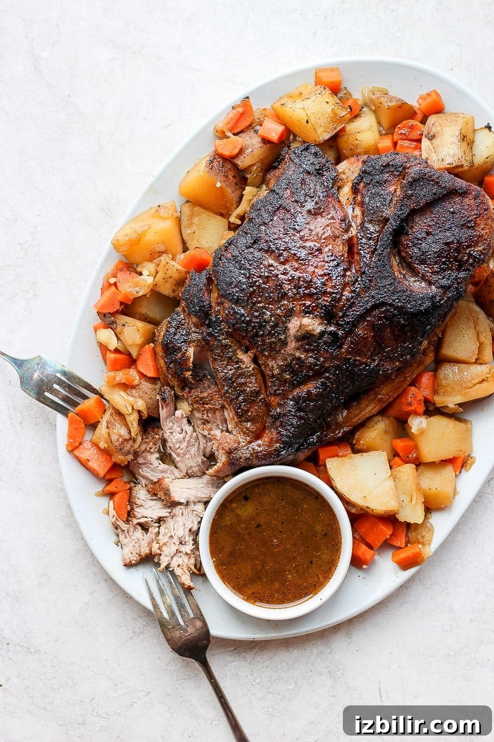 oven baked pork roast surrounded by potatoes and carrots