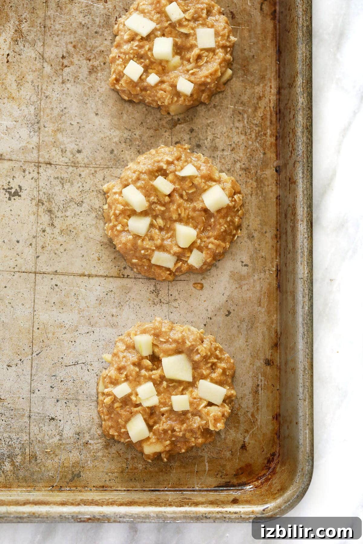 Soft Chewy Apple Oatmeal Cookies with Cinnamon 5 Apple oatmeal cookies on a baking sheet before they are baked.