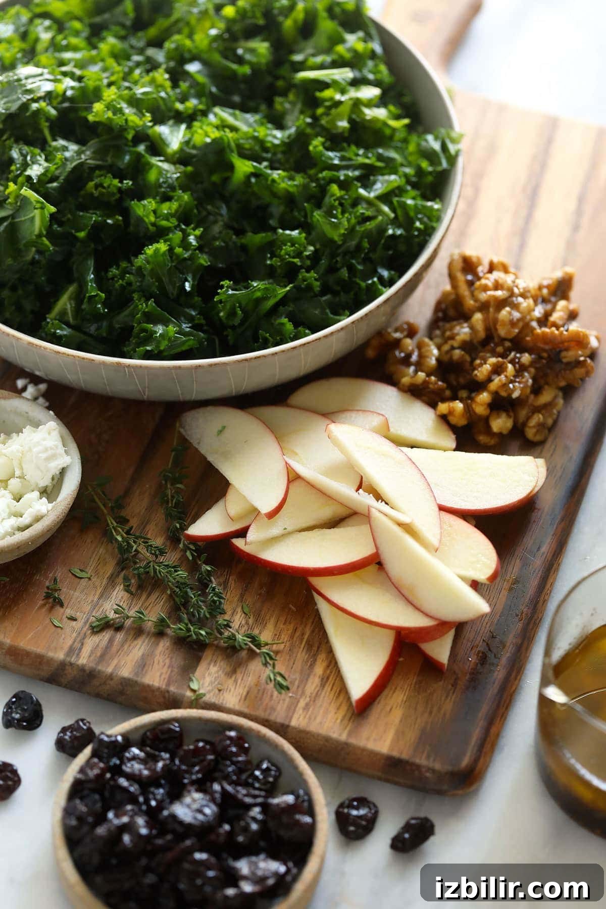 Looking for a last-minute Thanksgiving salad idea? Try a massaged kale, apple, and walnut salad with goat cheese and dried cherries. ingredients on cutting board