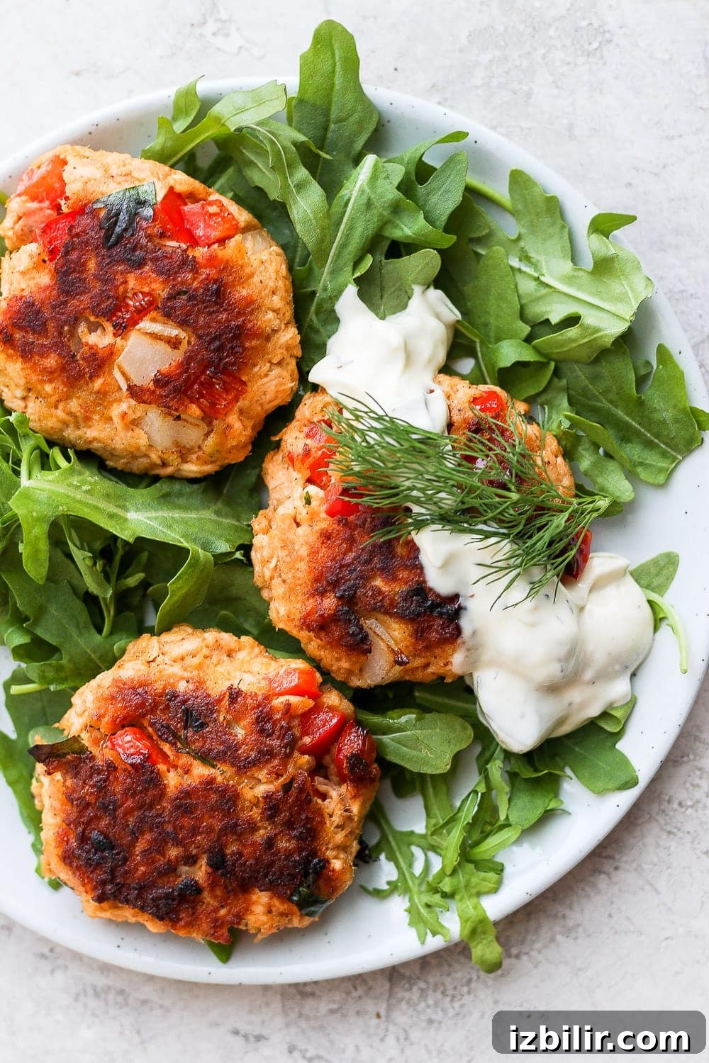 Salmon patties made with flaked salmon, panko, mayo and Tabasco salmon patties atop arugula with tartar sauce
