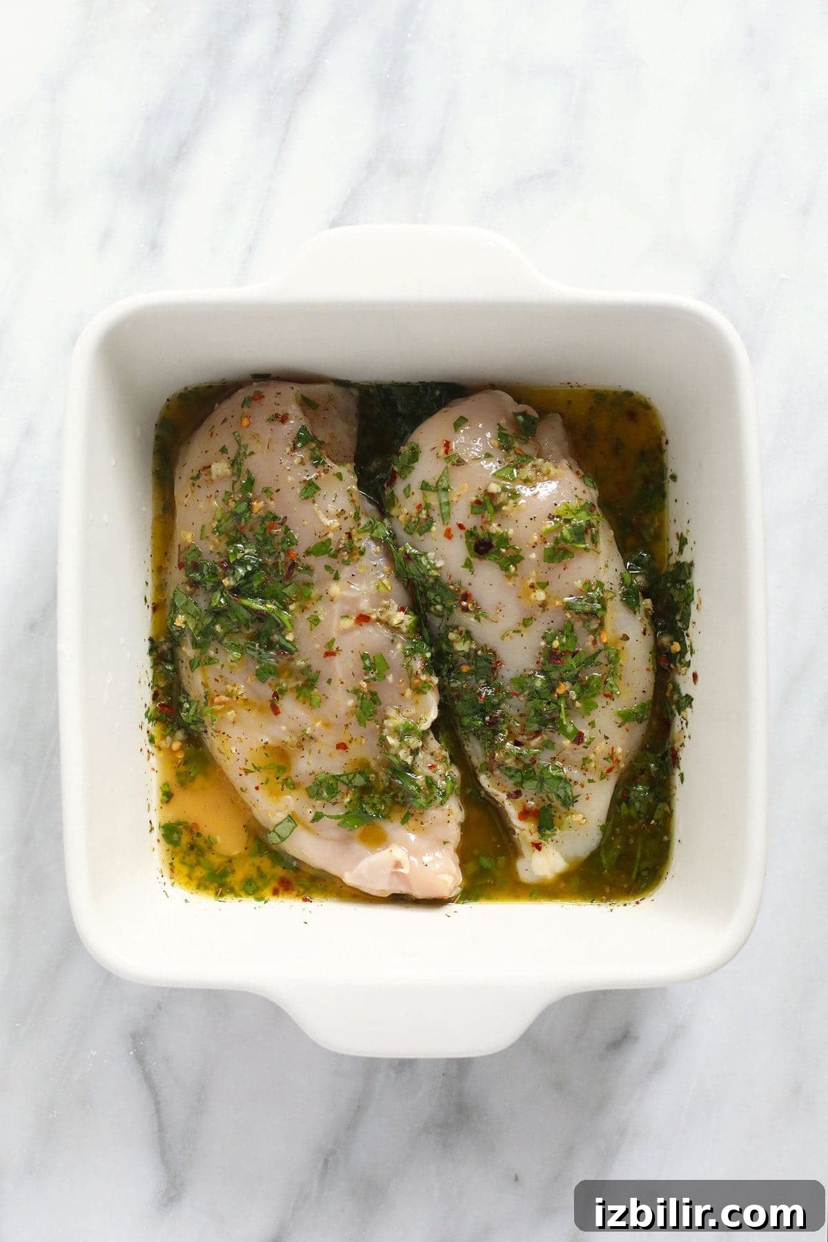 Chicken marinating in Italian dressing chicken marinating in dish.