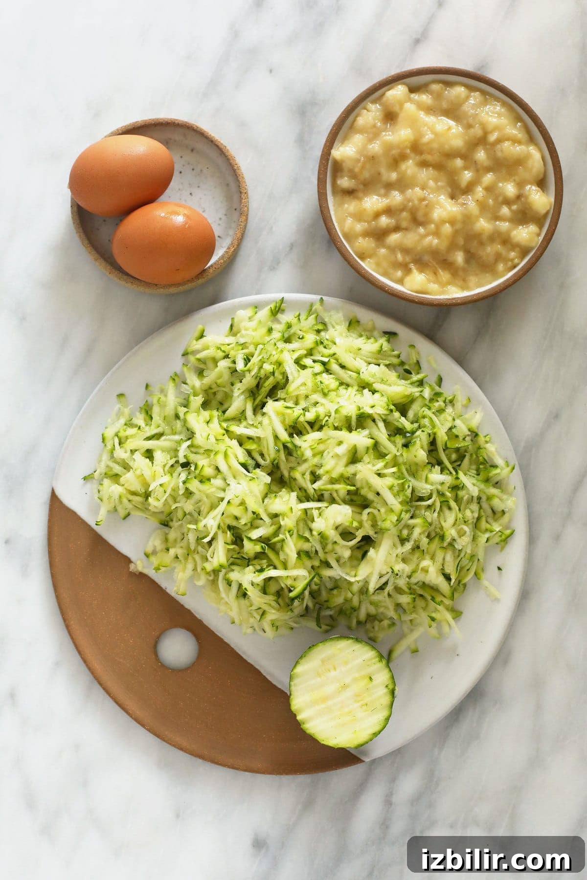 shredded zucchini, eggs, and mashed banana on plates.