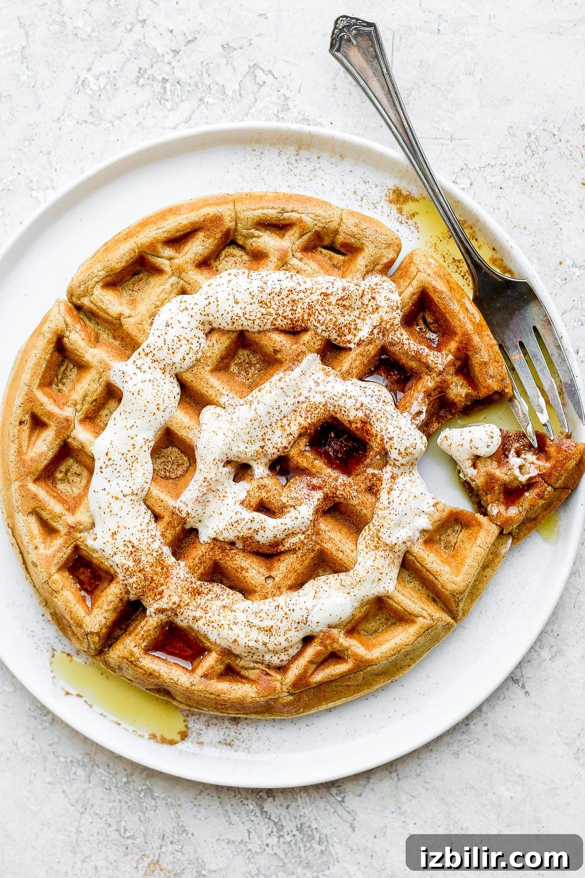 cinnamon roll waffles topped with a greek yogurt cream cheese drizzle