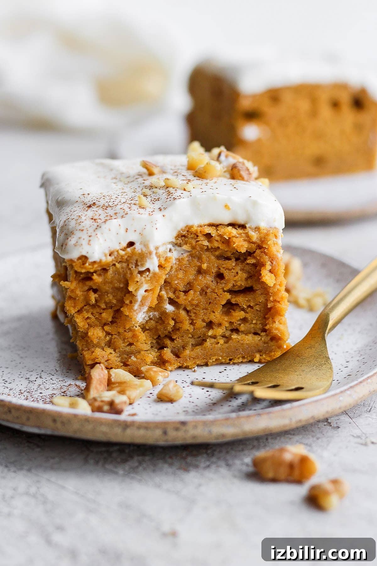 This pumpkin sheet cake is as easy as it is delicious. Packed with simple ingredients and topped with a yummy cream cheese frosting, this dessert can't be beat! slice of pumpkin sheet cake on a plate