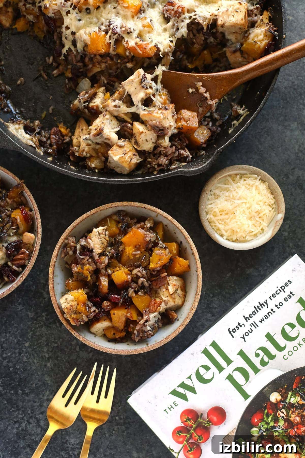 butternut squash wild rice casserole in a cast iron pan being scooped with a wooden spoon