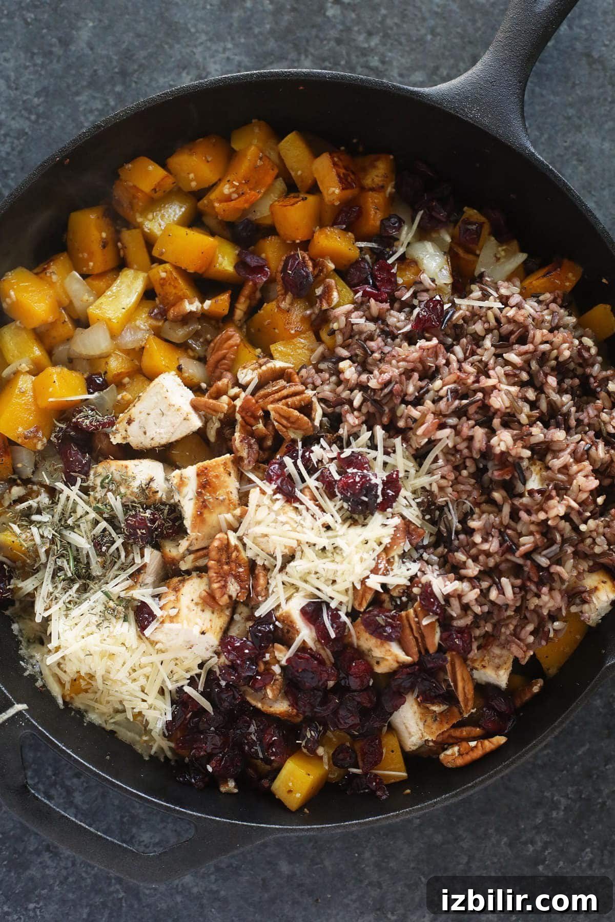butternut squash wild rice casserole in a cast iron pan ready to be mixed together and baked