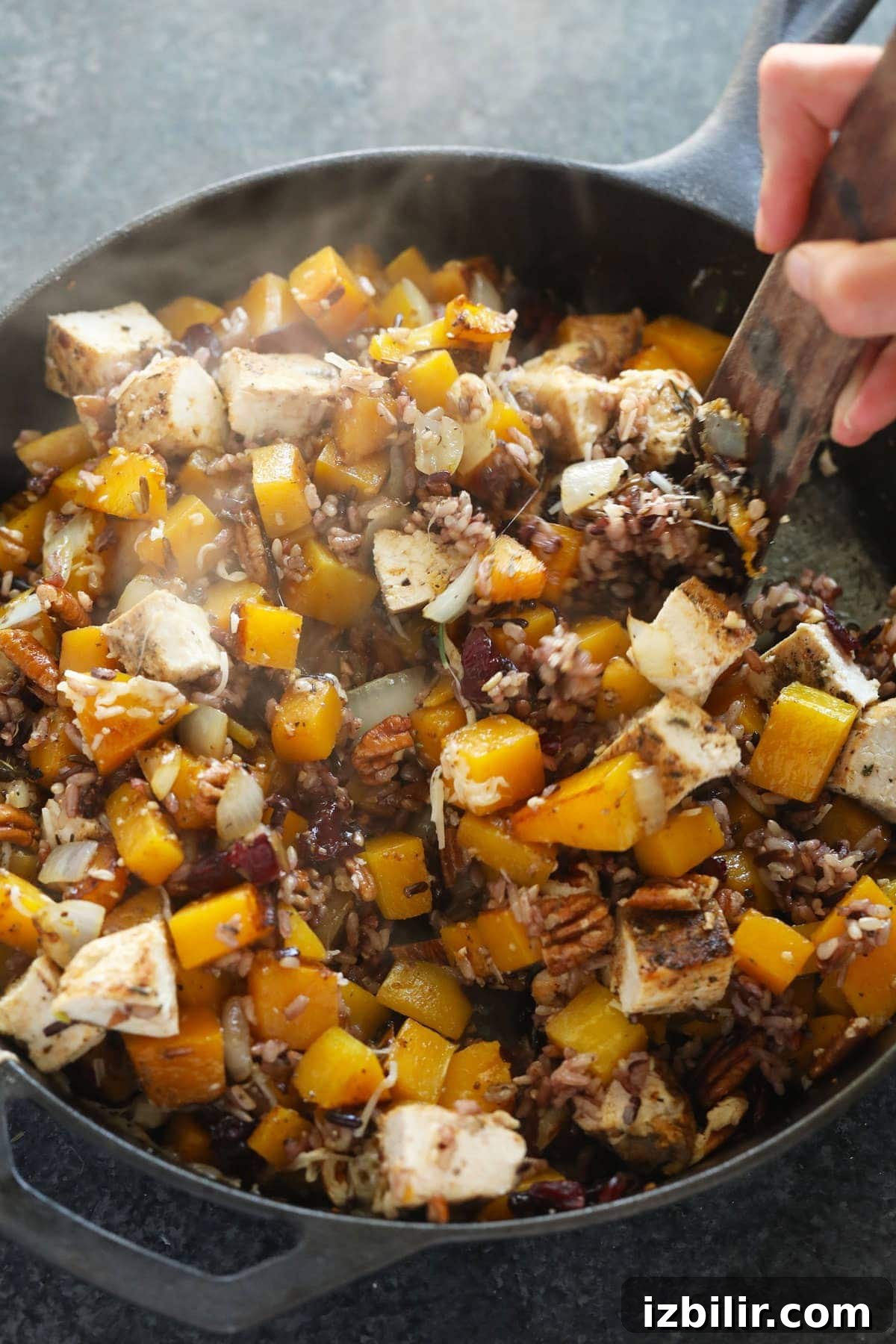 butternut squash wild rice casserole ingredients being mixed together in a cast iron pan