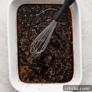 A bowl of brown liquid with a whisk.