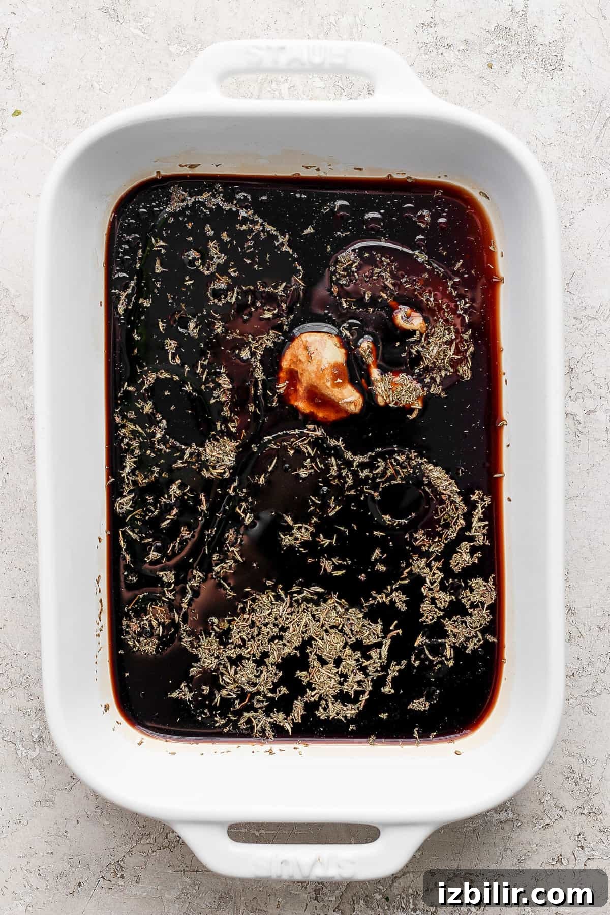 A white baking dish with a sauce in it.