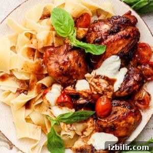 Grilled chicken with pasta and tomatoes on a plate.
