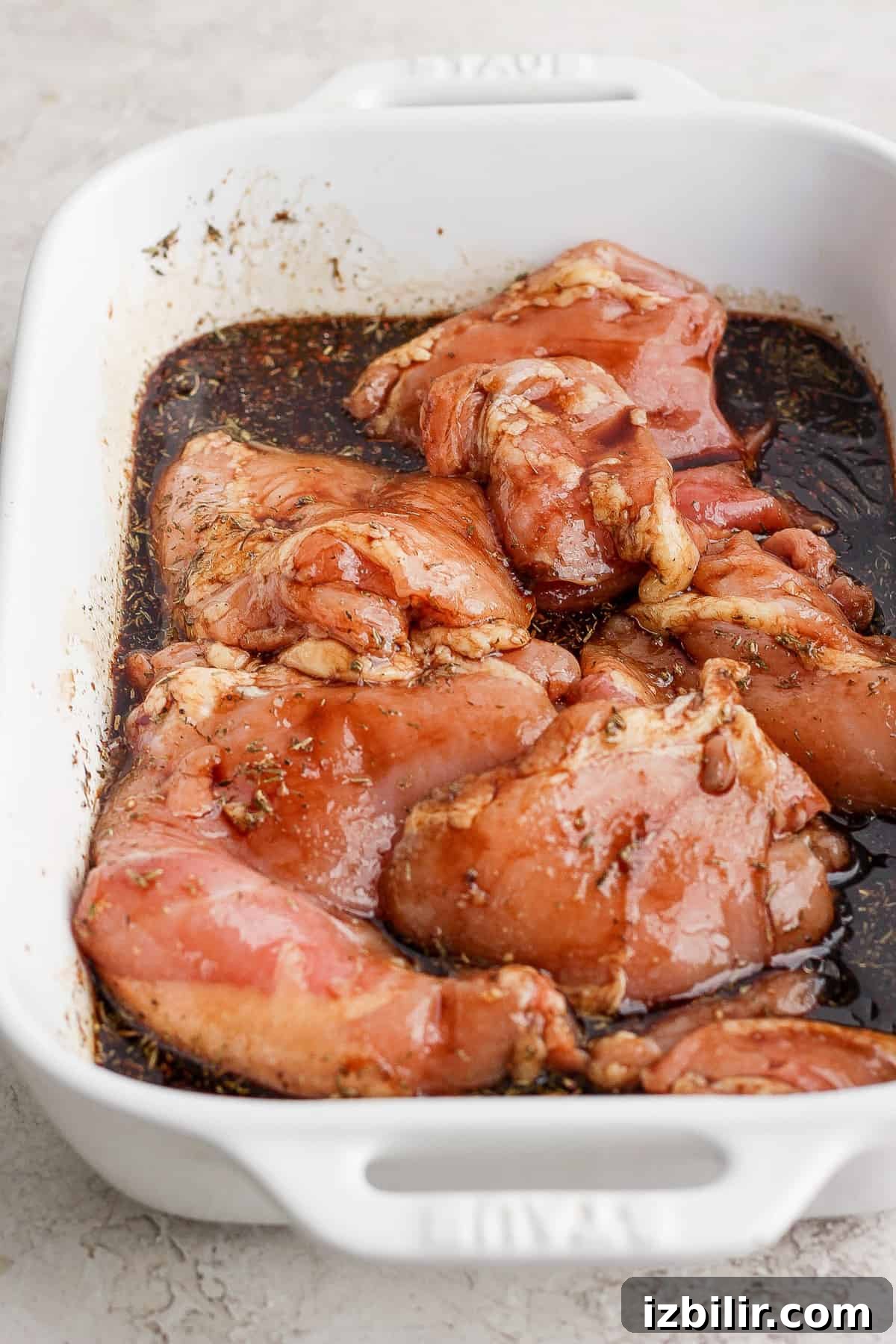 Chicken breasts in a baking dish with sauce.