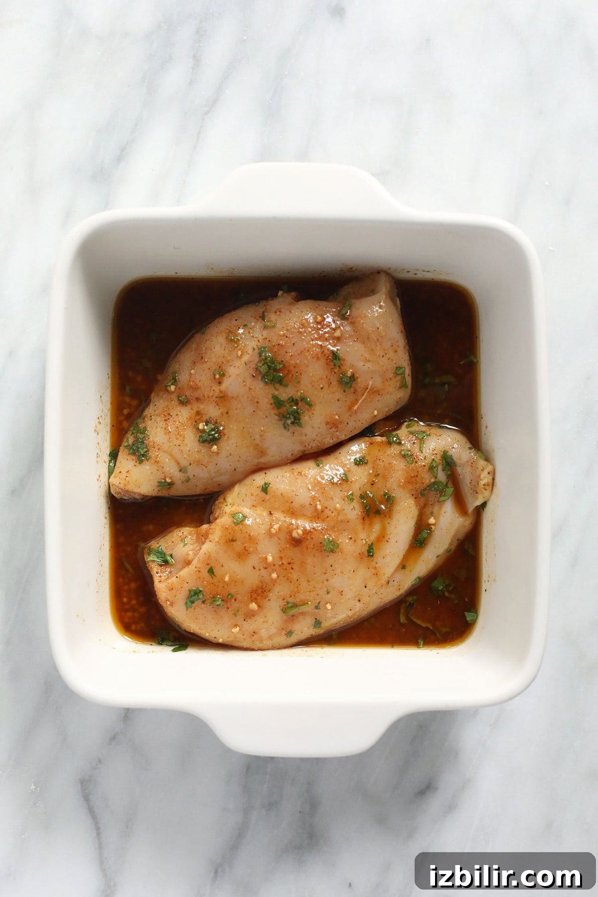 Chicken marinating in a casserole dish.