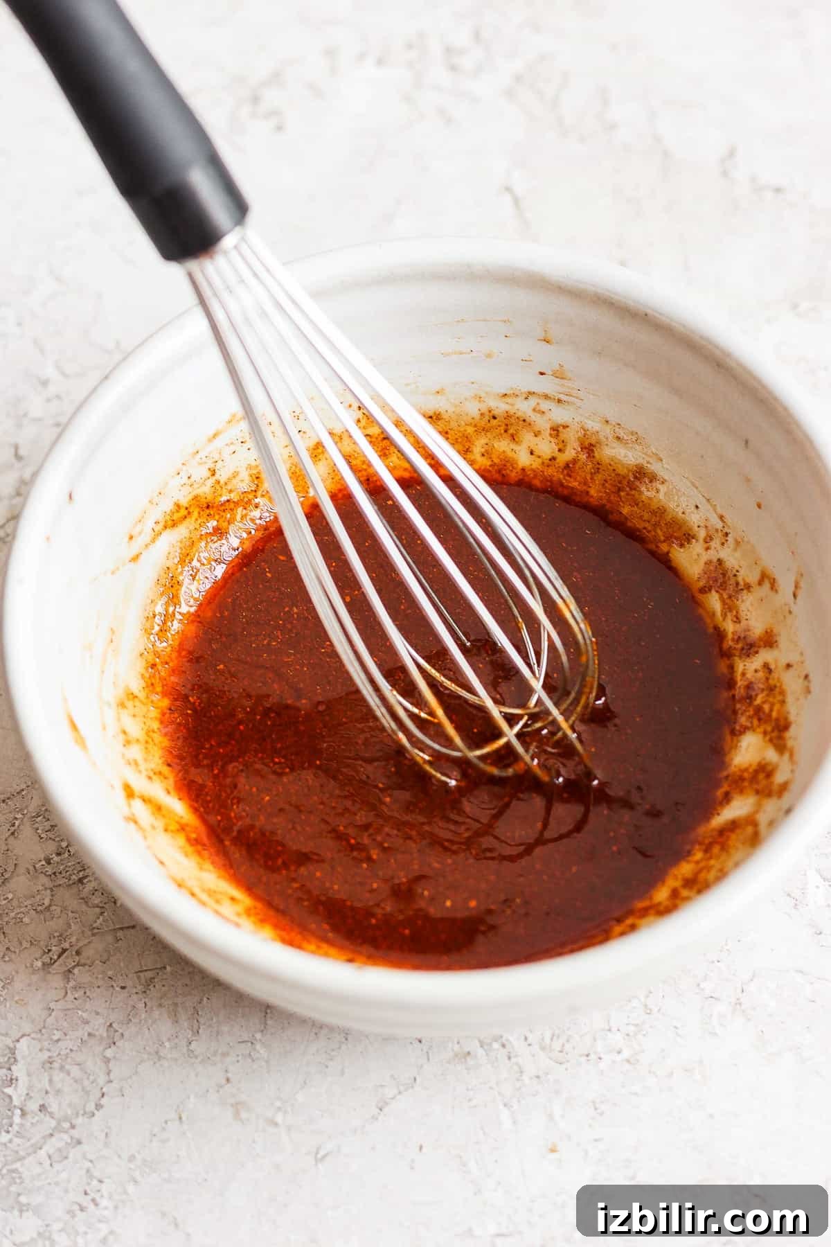 a bowl of sauce with a whisk in it.