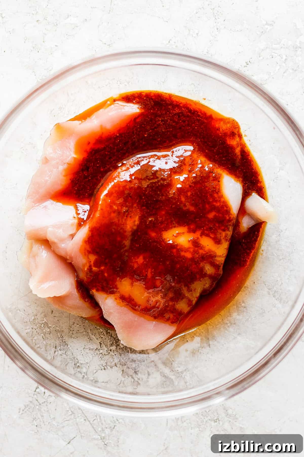 a piece of chicken in a bowl with sauce on it.