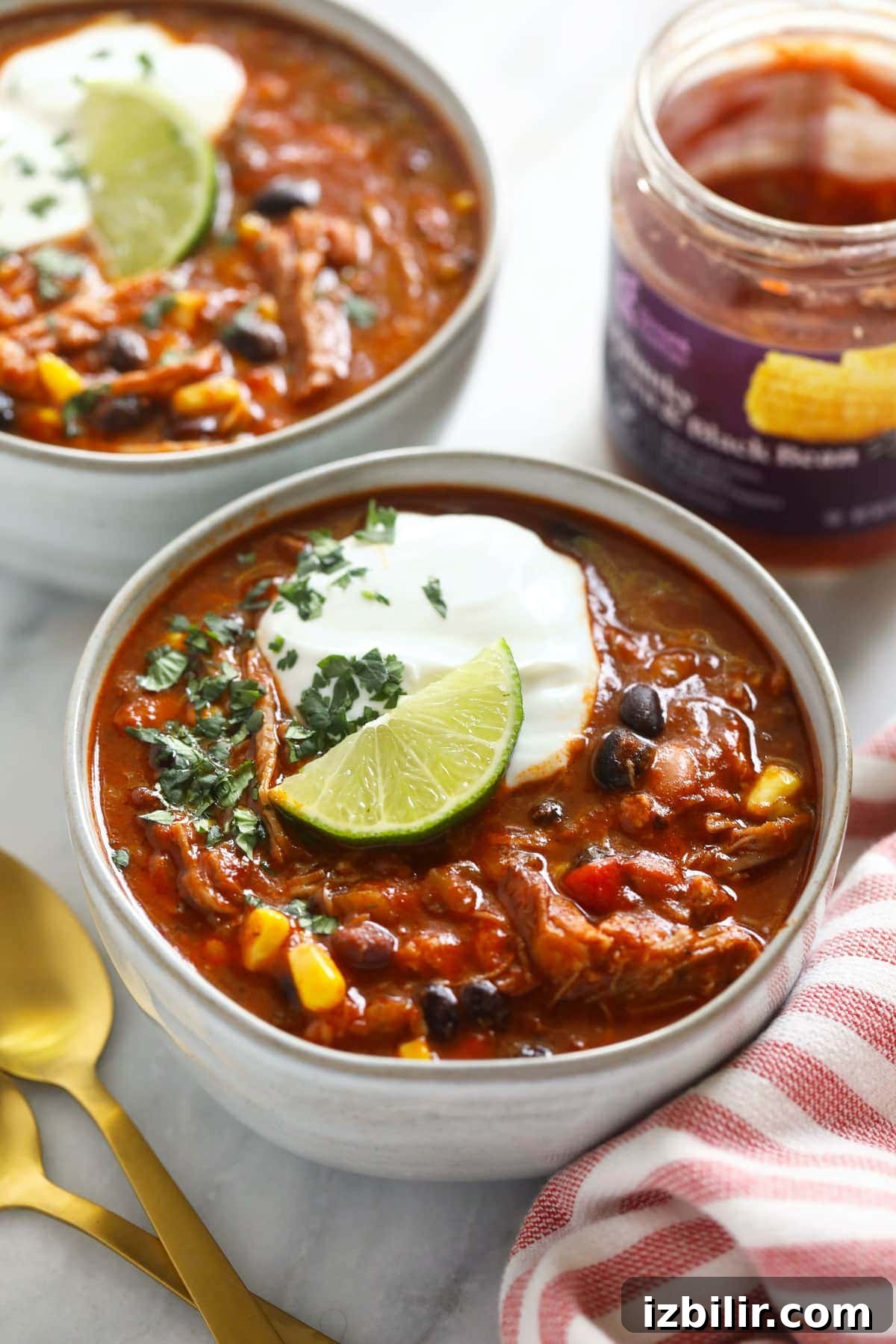 pork chili in bowl with Greek yogurt and a lime wedge.