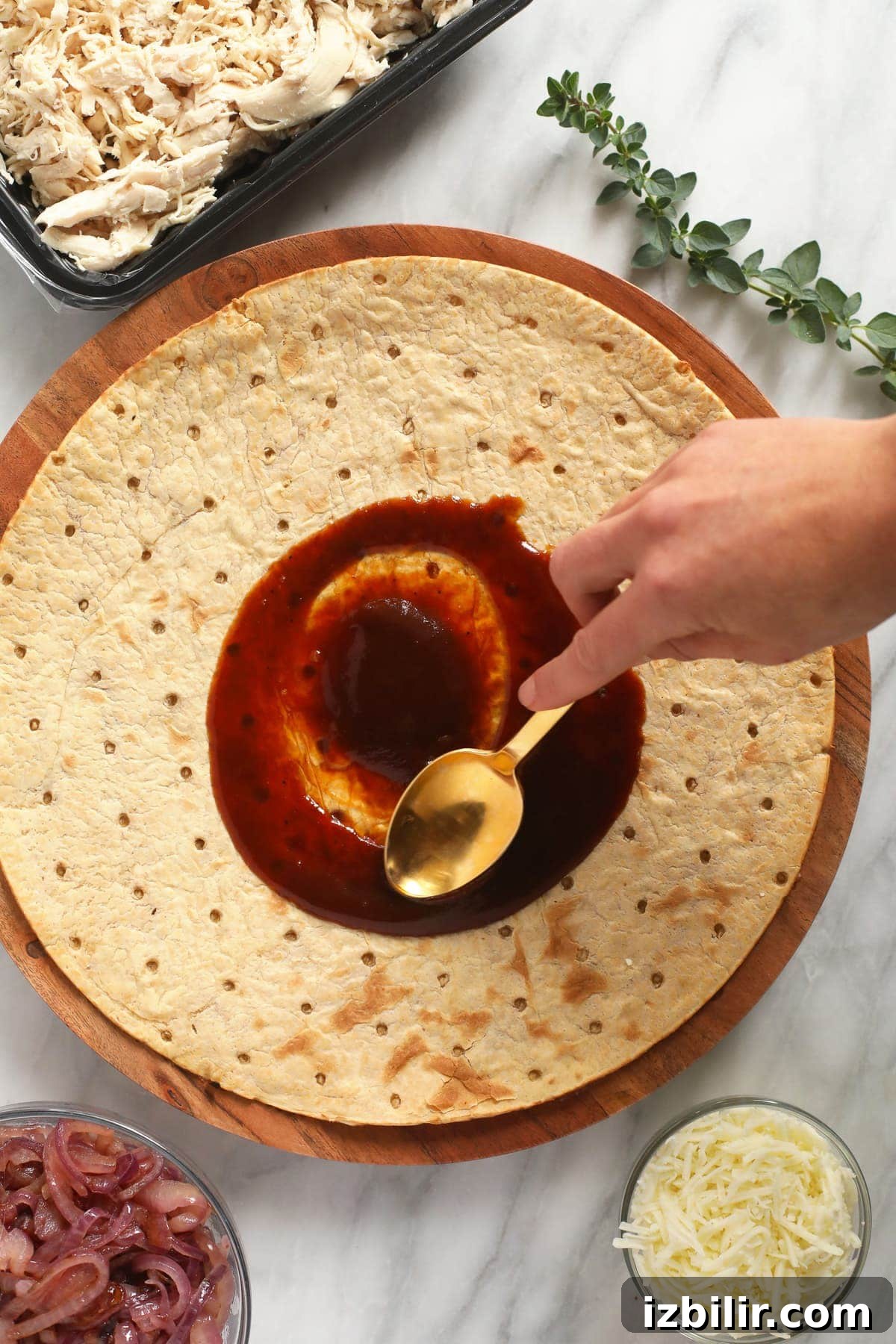 spreading bbq sauce on pizza crust