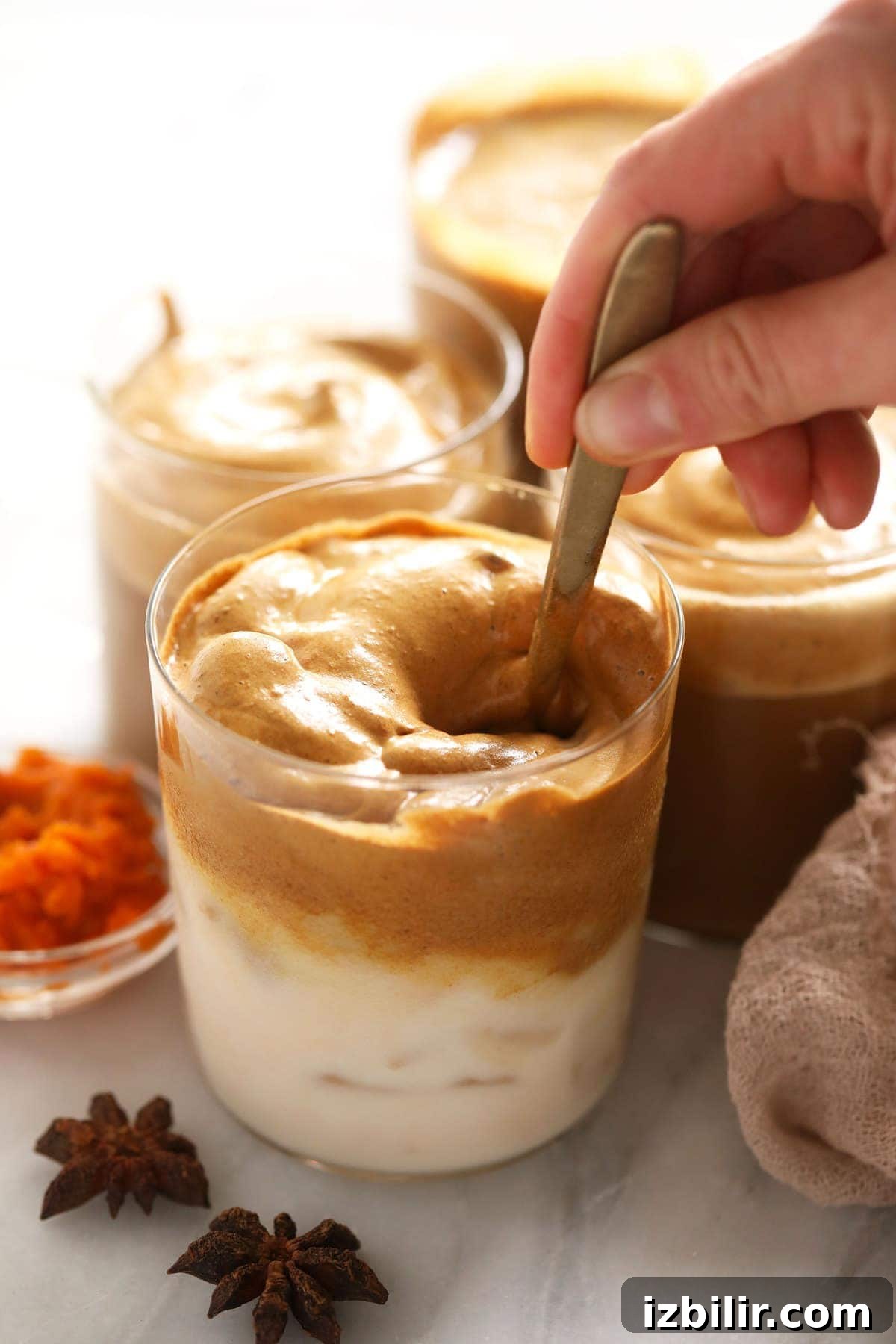 Pumpkin Spice Dalgona Coffee Recipe 5 Mixing dalgona coffee and almond milk together with a spoon.