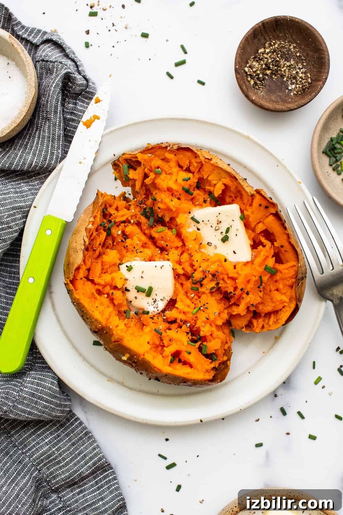 Baked sweet potatoes are a delicious addition to any meal. Baked sweet potato on a plate topped with butter.