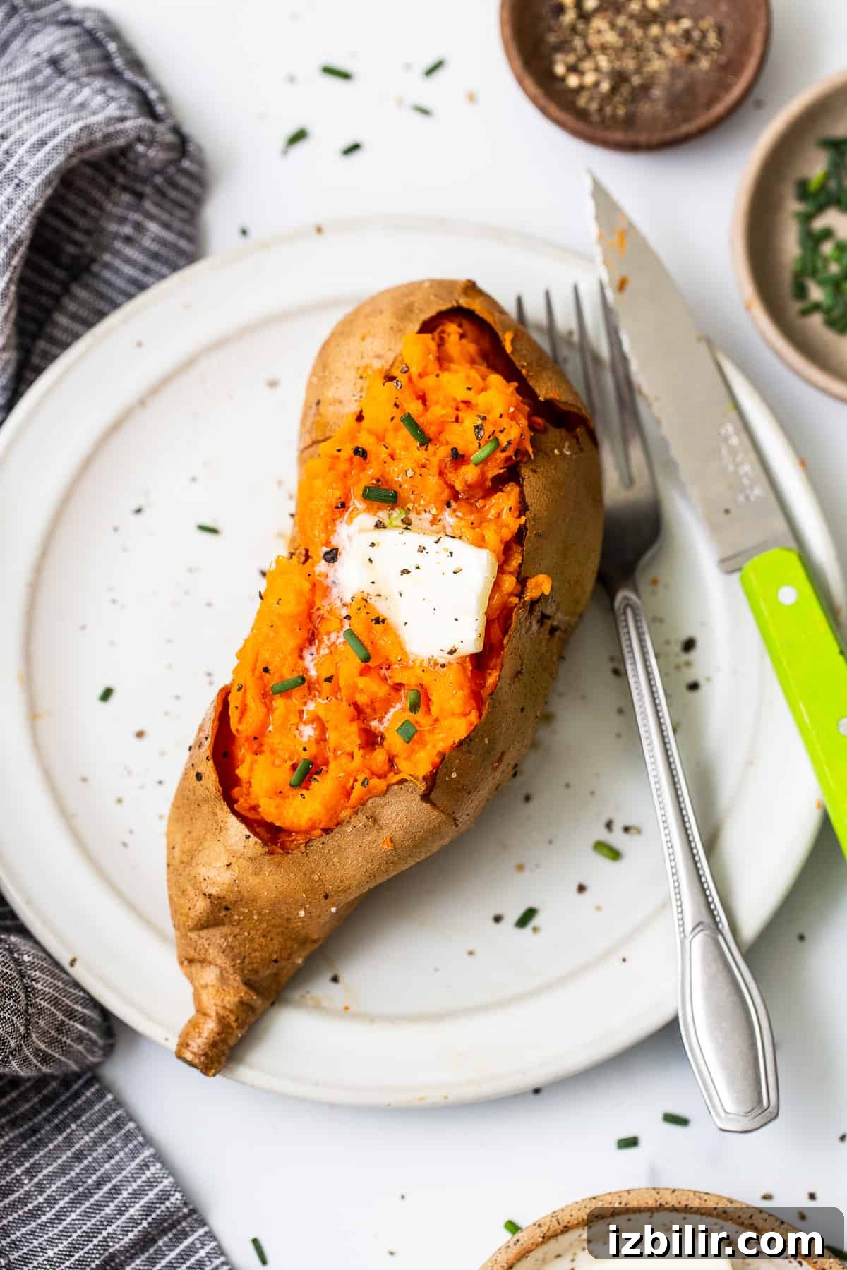 Baked sweet potato on a plate. Baked sweet potato on a plate topped with butter.