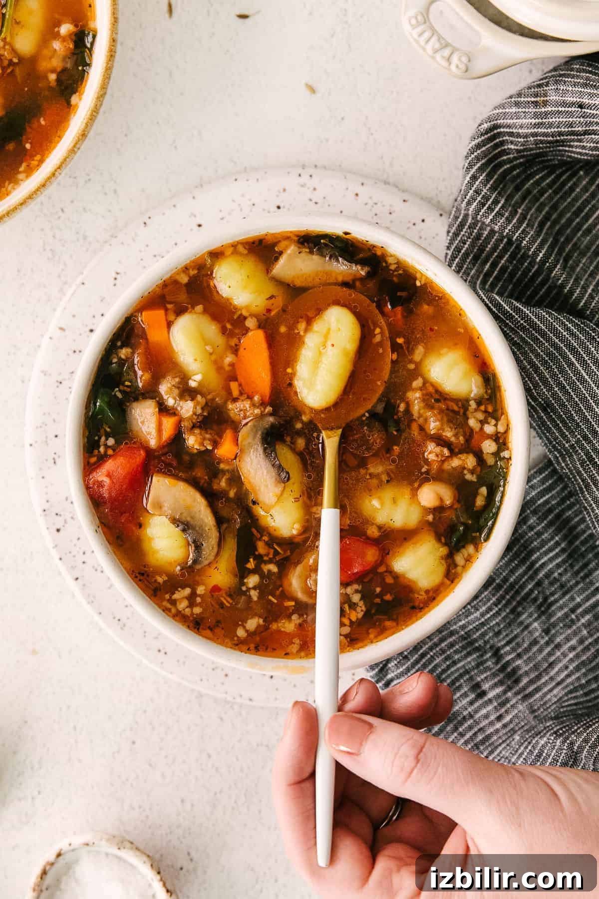 sausage gnocchi soup in a bowl with one gnocchi on a spoon