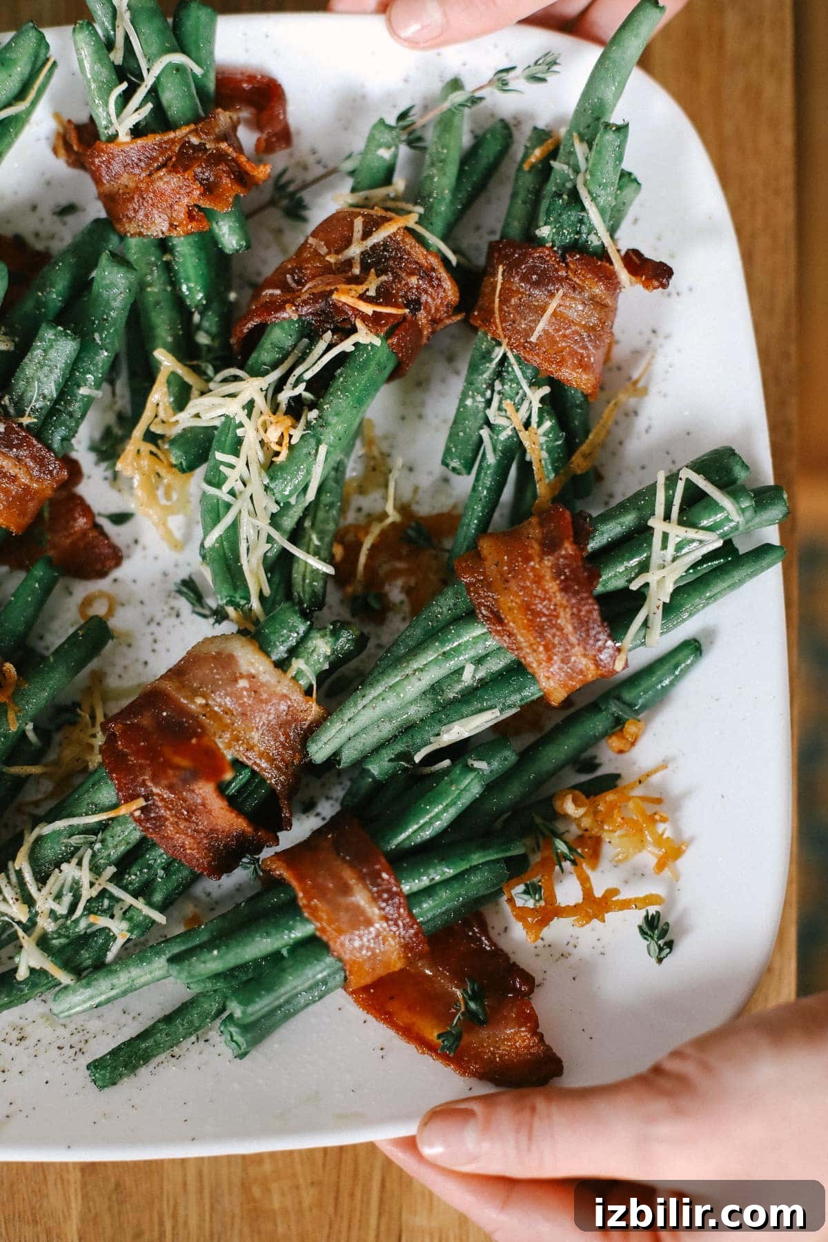 bacon wrapped green beans on a plate topped with parmesan cheese