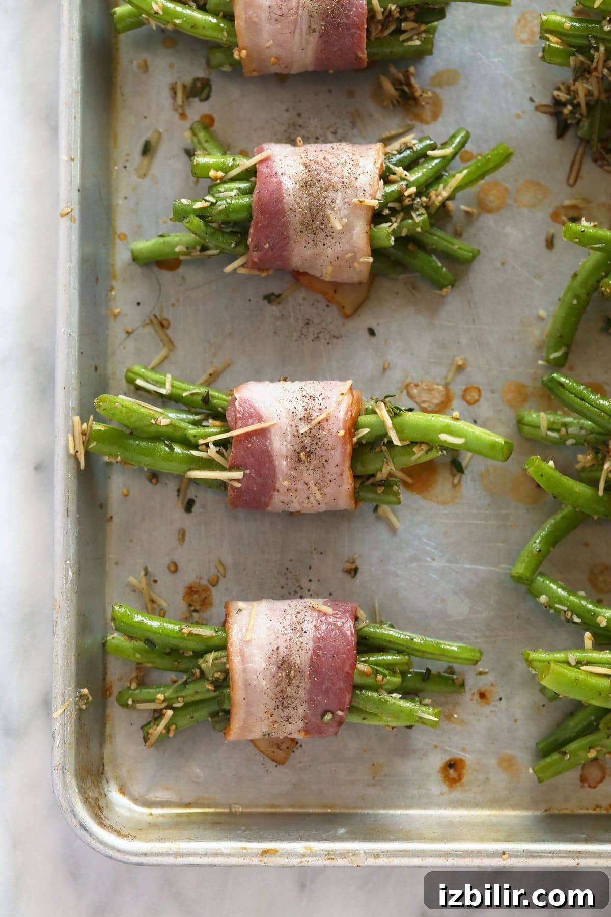 bacon wrapped green beans ready to be baked on a baking sheet