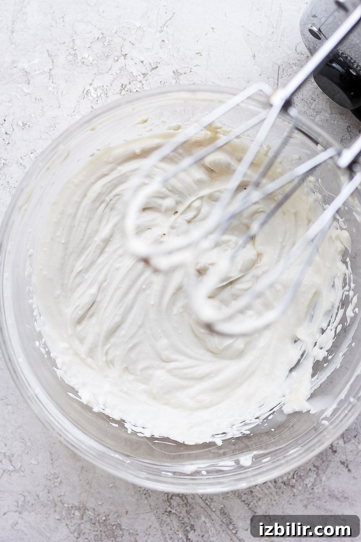 This Greek yogurt cream cheese frosting is the most delicious healthy cream cheese frosting we've ever had! Cream cheese frosting with hand mixer in bowl.