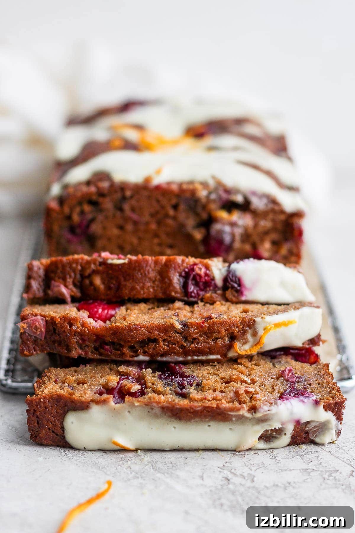 cranberry orange bread with a cream cheese glaze cut into slices
