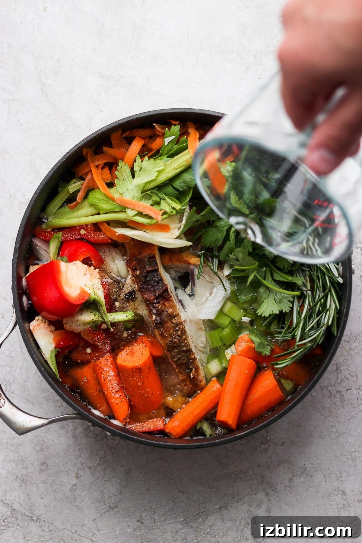 Pouring water into a pot full of vegetables.