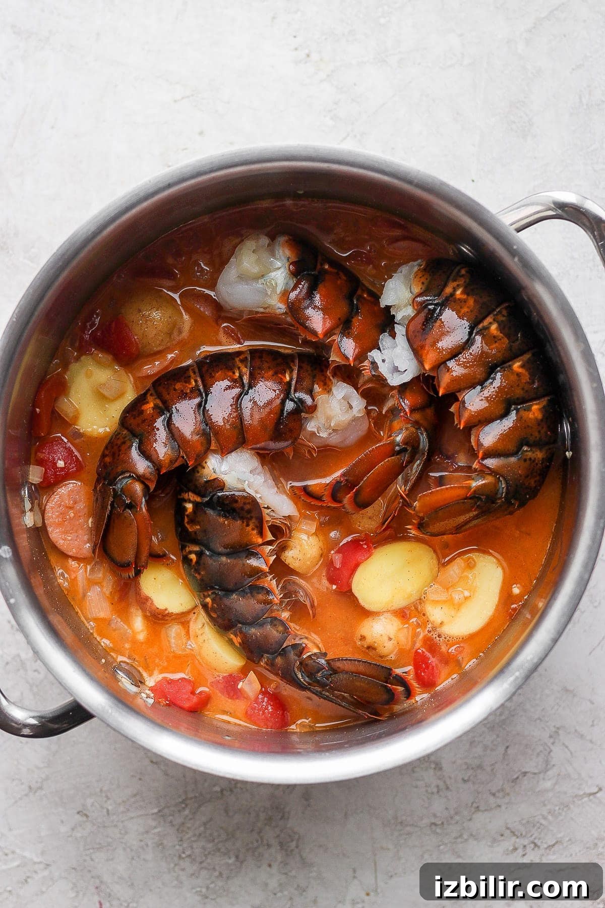 raw lobster tails being added to the seafood boil broth