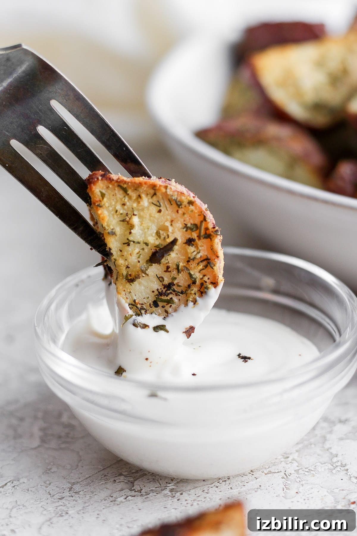 These Ranch Roasted Potatoes are flavor-packed and deliciously crispy! Whip up a batch for the most flavorful side dish. roasted red potato being dipped into ranch dressing