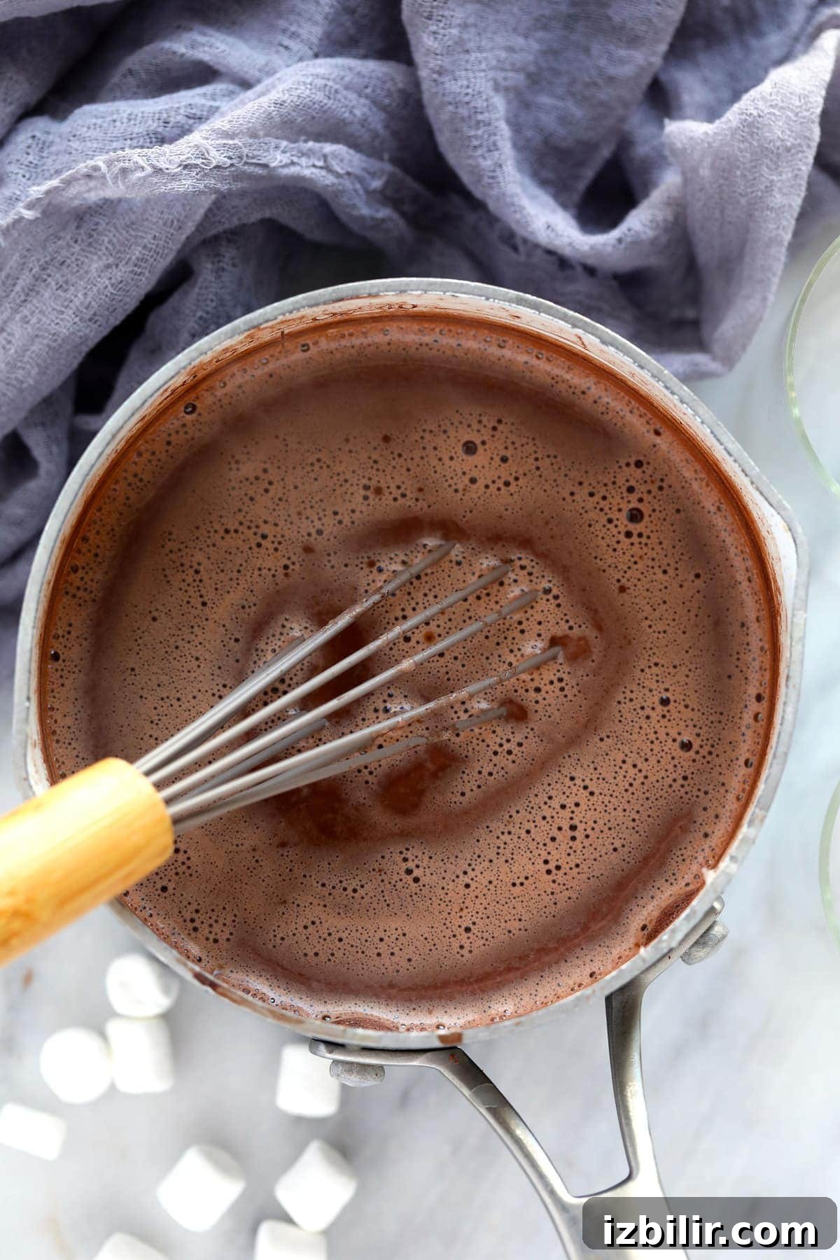 Spiked hot chocolate simmering in a pot while being whisked