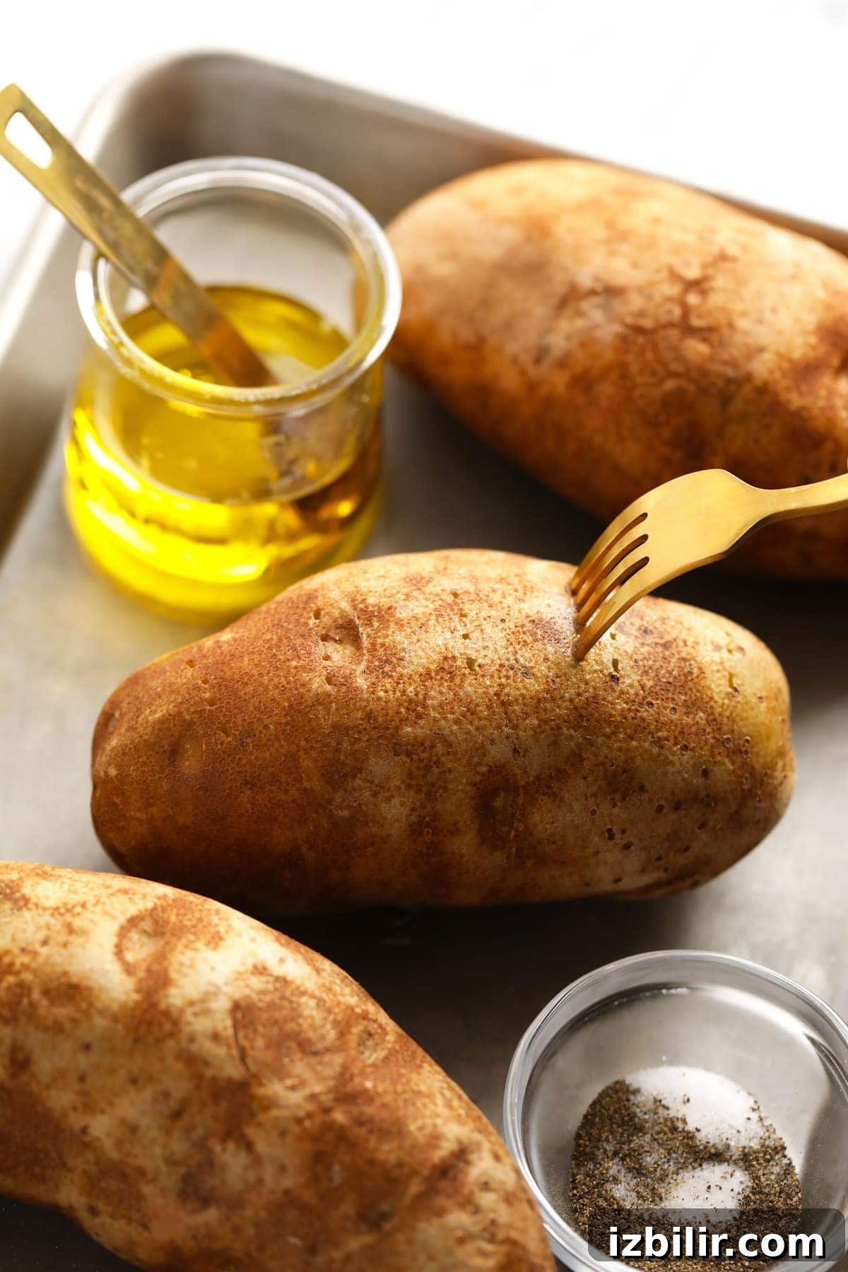 Close up of baked potato halves with butter and chives.