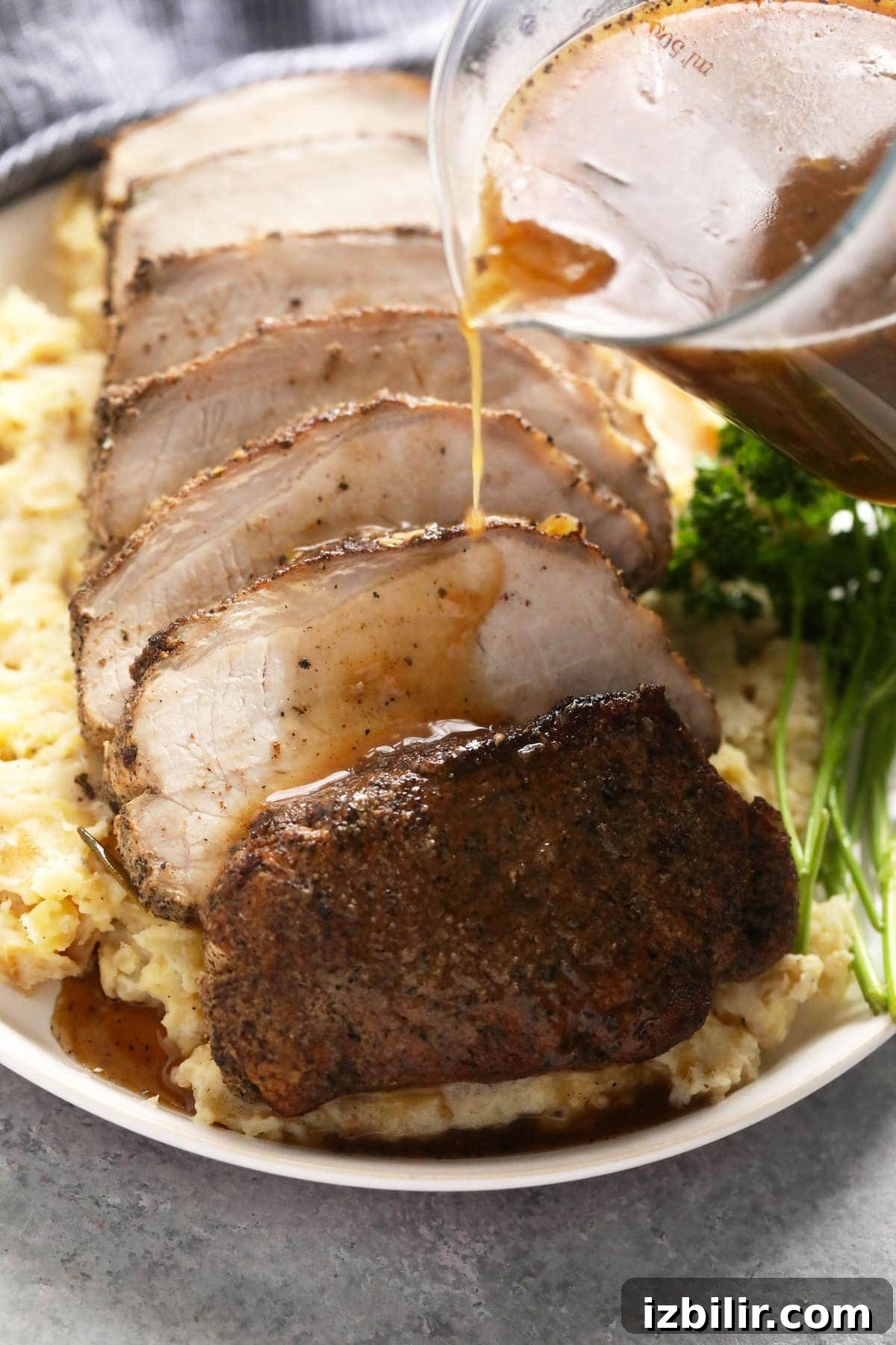 Slow cooker pork loin sliced on a bed of mashed potatoes.