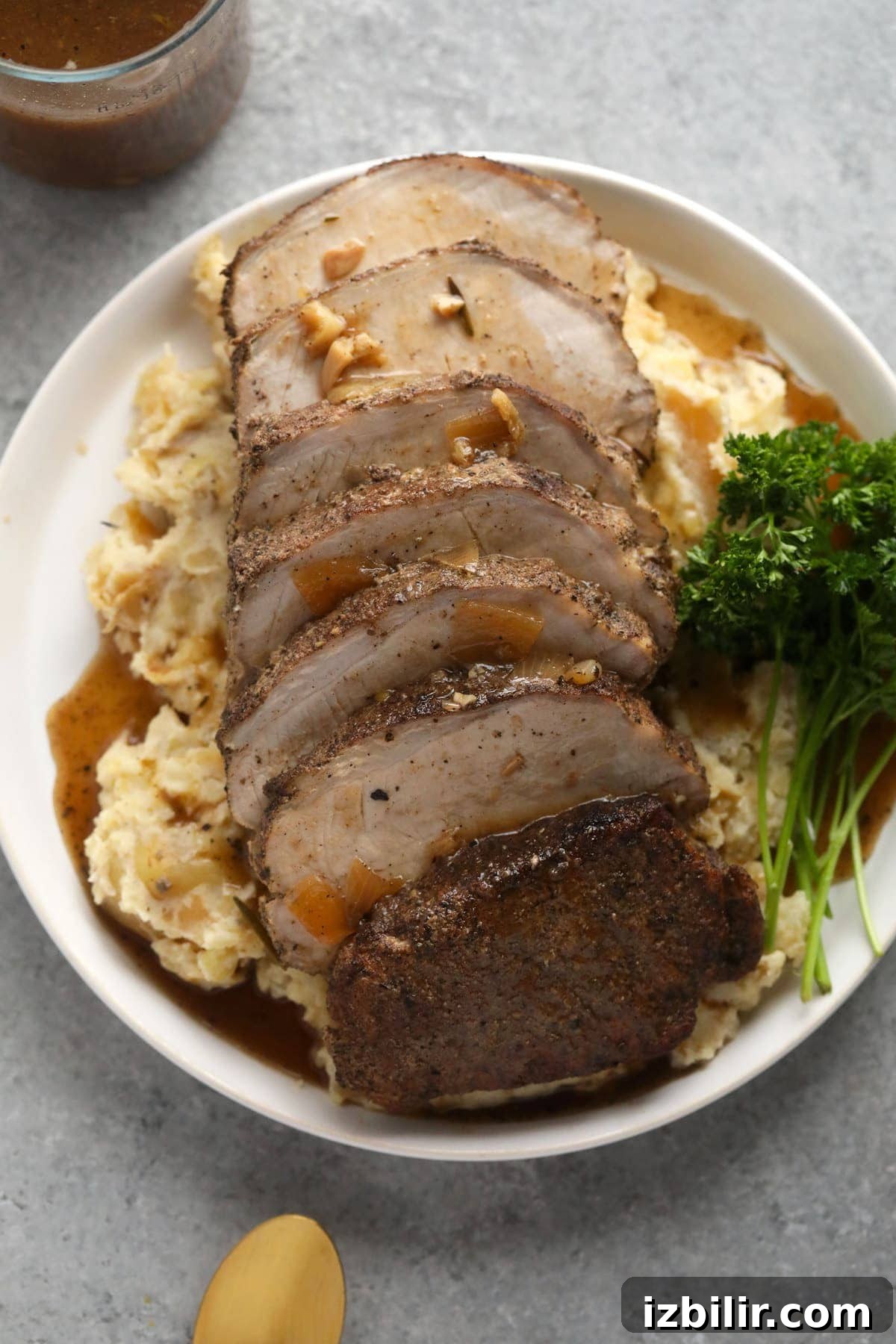 Slow cooker pork loin on a bed of mashed potatoes covered in gravy.